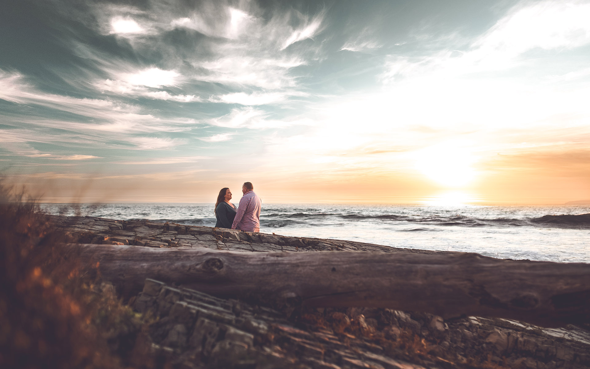 couple standing at beach sunset during engagement