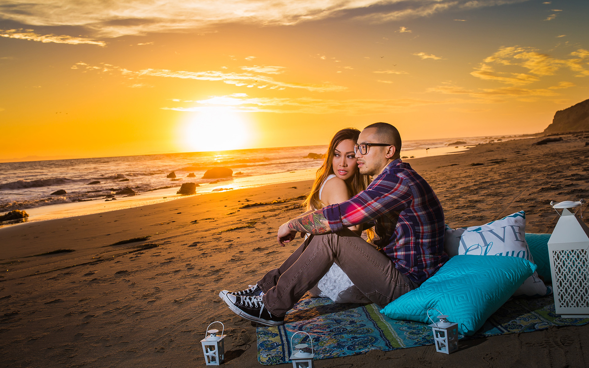 man and woman sitting at beach sunset engagement photography